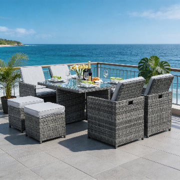 Outdoor patio set with table and chairs on a deck overlooking the ocean.