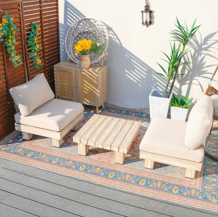Direct Wicker outdoor patio set with beige chairs, wooden table, and decorative elements on a deck.