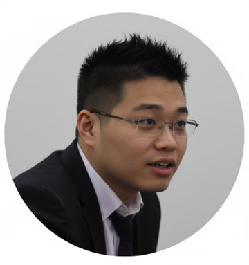 Circular portrait of the CEO of Direct Wicker wearing glasses and a dark suit on a light gray background.