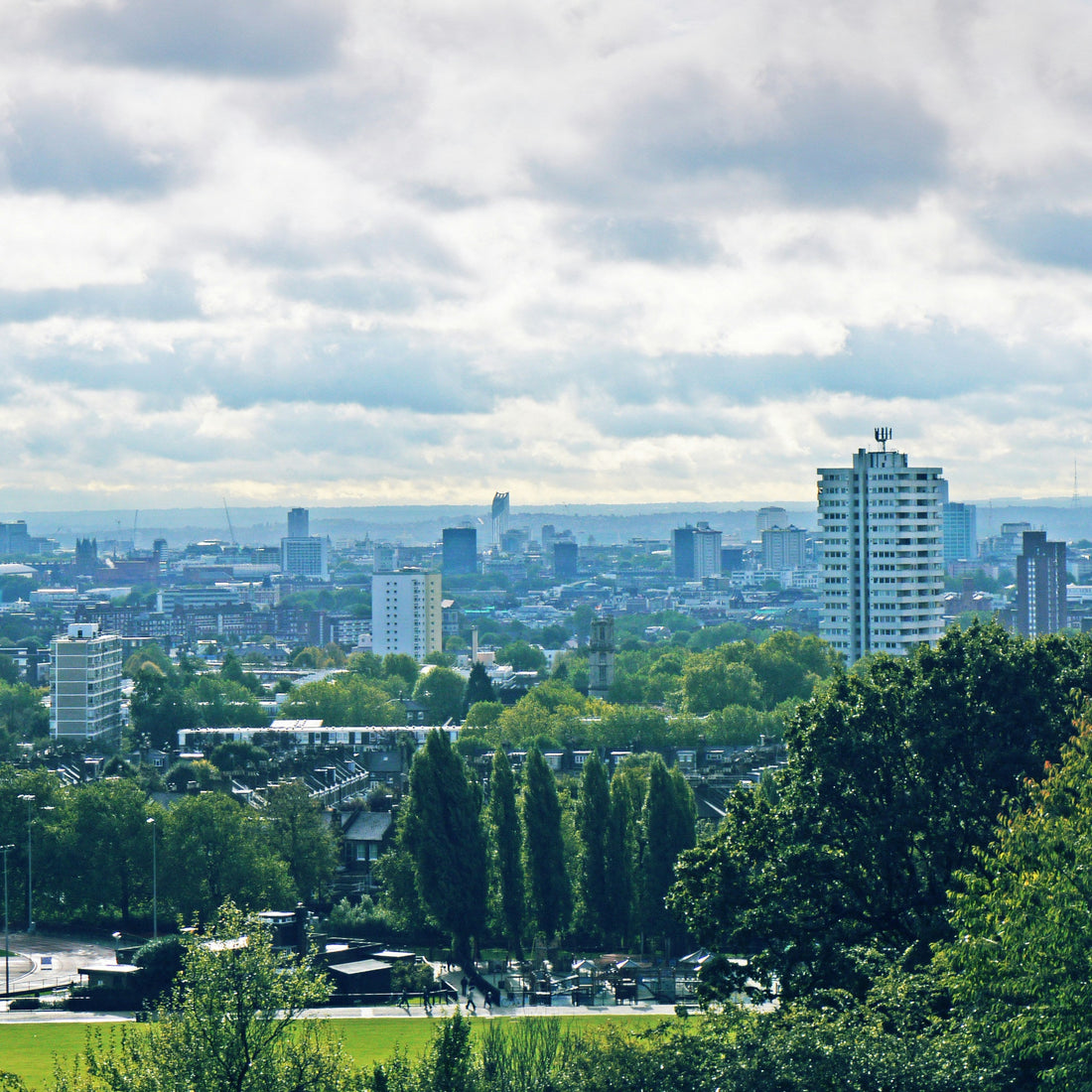 Cityscape with modern buildings and green trees under a cloudy sky, where Direct Wicker's parent company was established