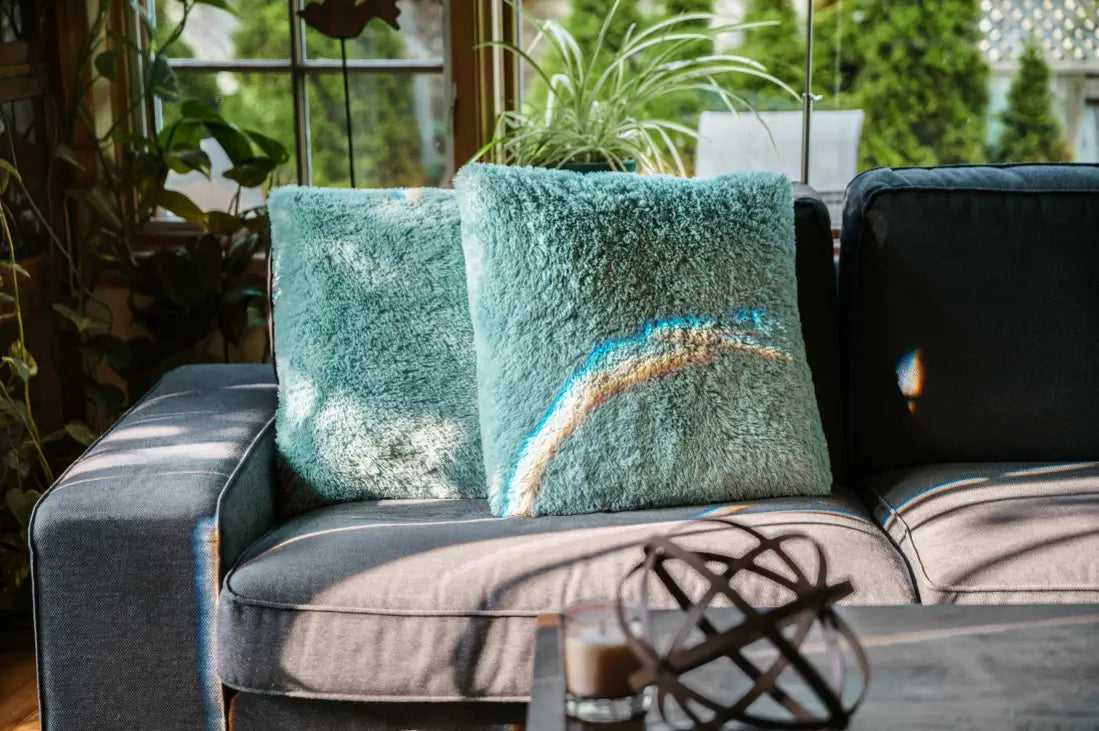 Turquoise textured pillows on a gray sofa with a decorative object